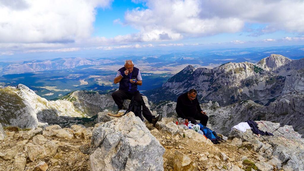 Mountaineer having a well deserved lunch at the top of Bobotov Kuk - Durmitor National Park