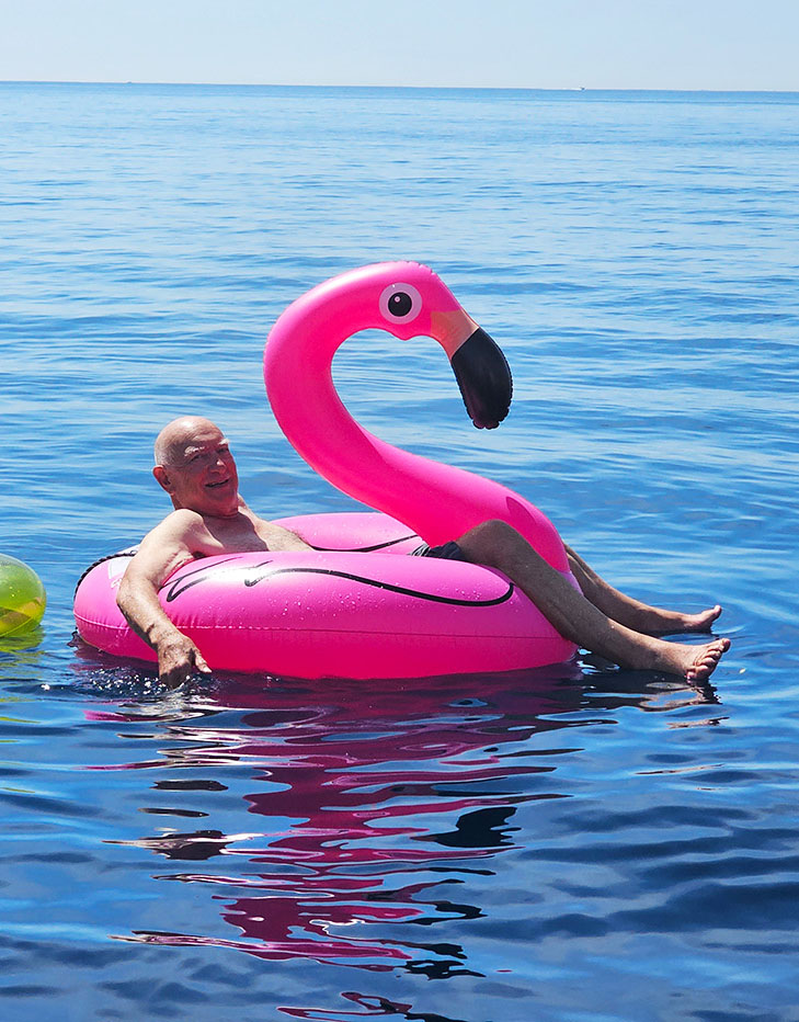 Guest relaxing on a pink flamingo float in calm blue water