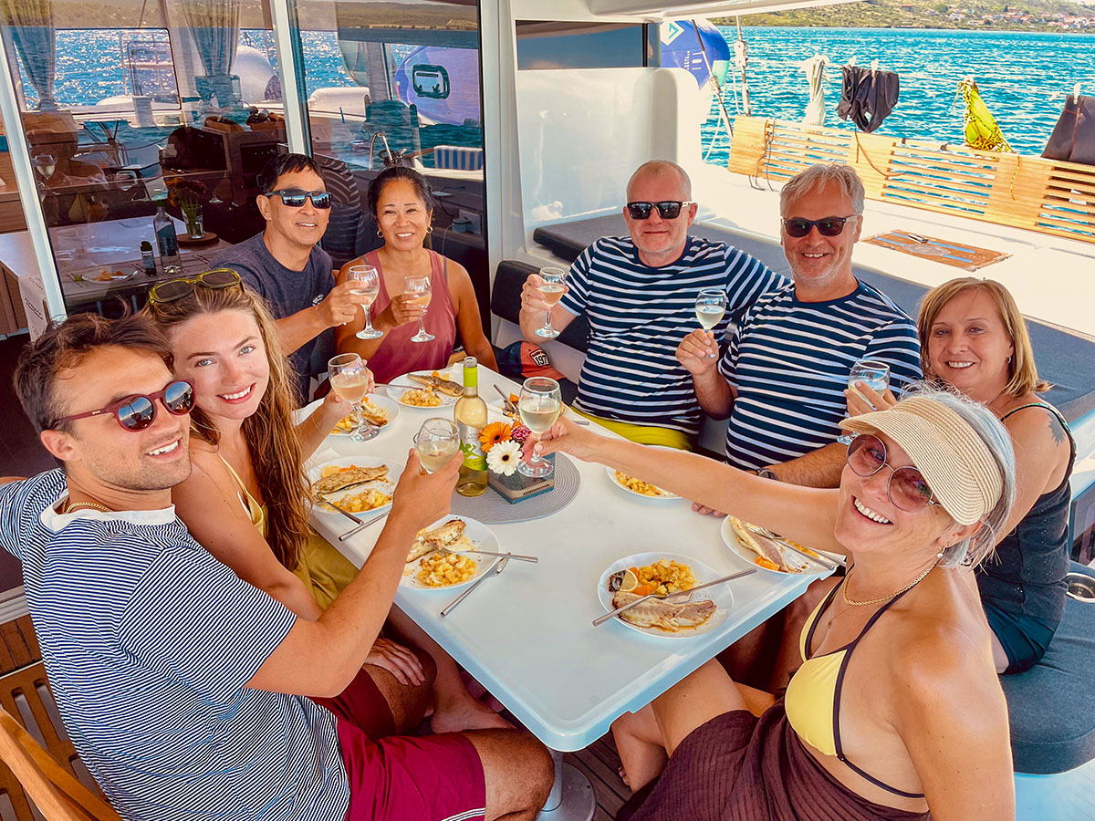 Guests gathered around a shared meal in the catamaran cockpit