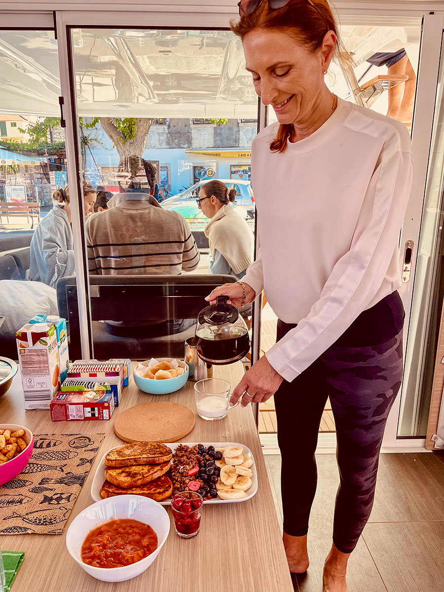 Woman pouring coffee beside a freshly prepared breakfast in the galley