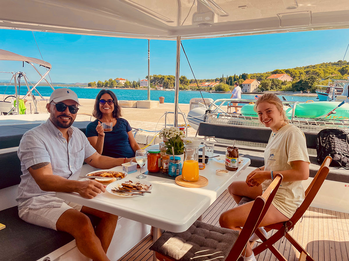 Three guests dining in the shaded cockpit overlooking the water