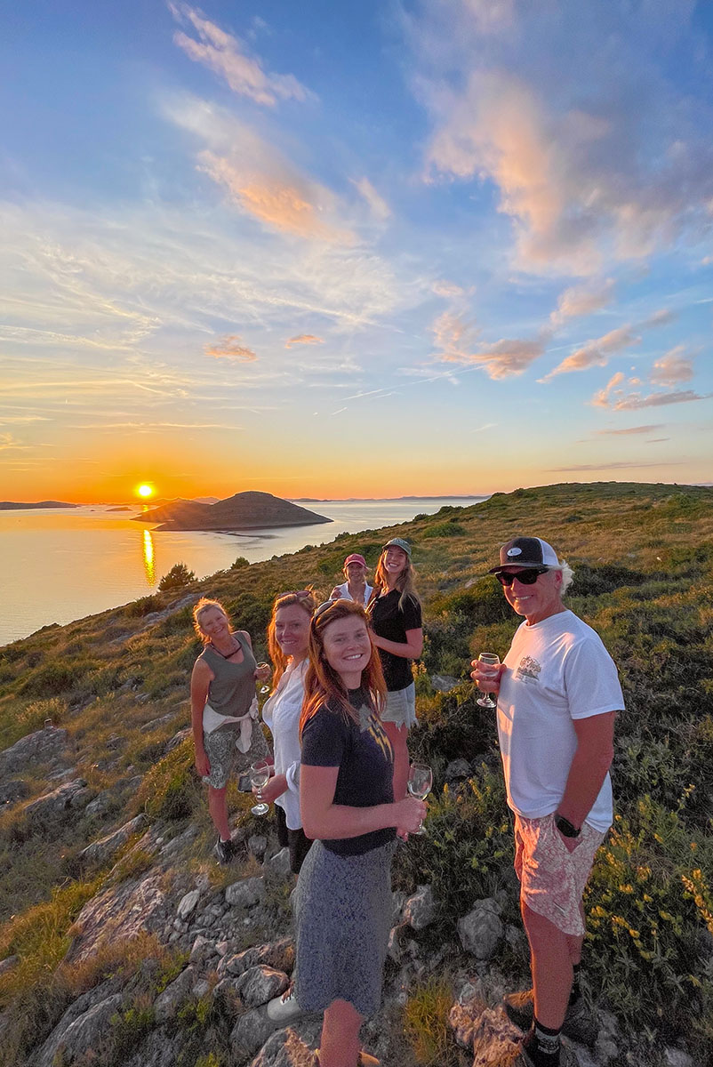 Travellers at an island sunset viewpoint