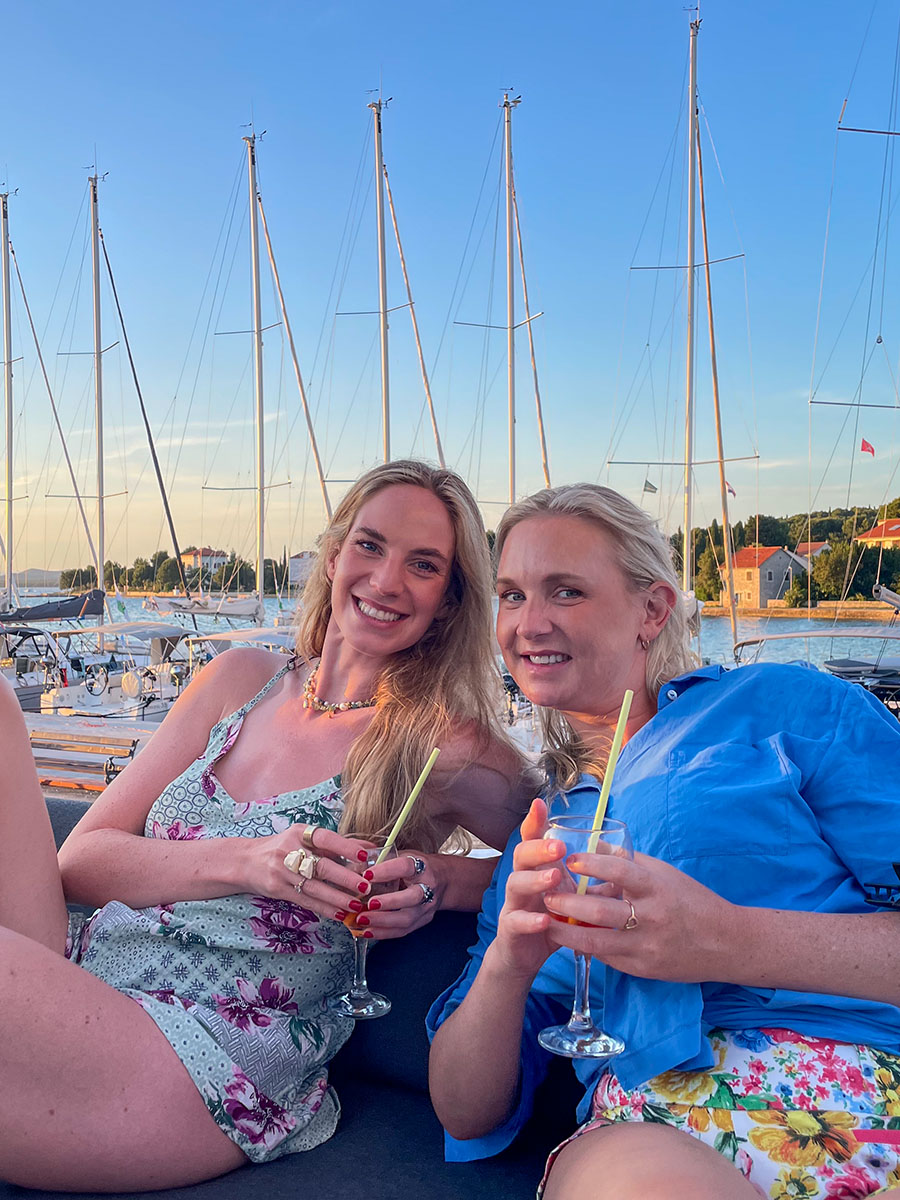 Two guests enjoying drinks on board beside a marina